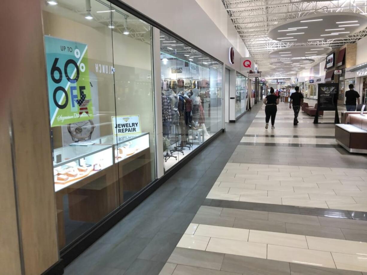 A few shoppers wander through the empty hallways of an outlet mall Tuesday, March 17, 2020, in Lakewood, Colo. Many of the stores were closed in the mall because of the coronavirus outbreak. (AP Photo/David Zalubowski) (Ted S.