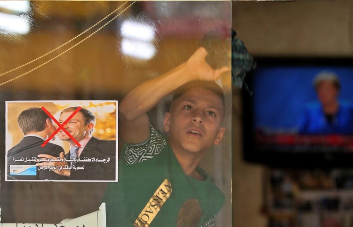 A young worker cleans the window of a barbershop that posts a warning sign referring to the coronavirus, with Arabic that reads, &quot;Please greet only and don&#039;t kiss, due to the difficult circumstances in the current situation&quot; on March 19 in Baghdad, Iraq.