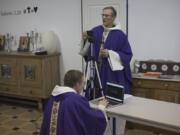 Priest Philippe Rochas, left, and Jean-Benoit de Beauchene pack up livestreaming equipment after holding a closed door Sunday mass at the St. Vincent de Paul church in Marseille, southern France, Sunday.