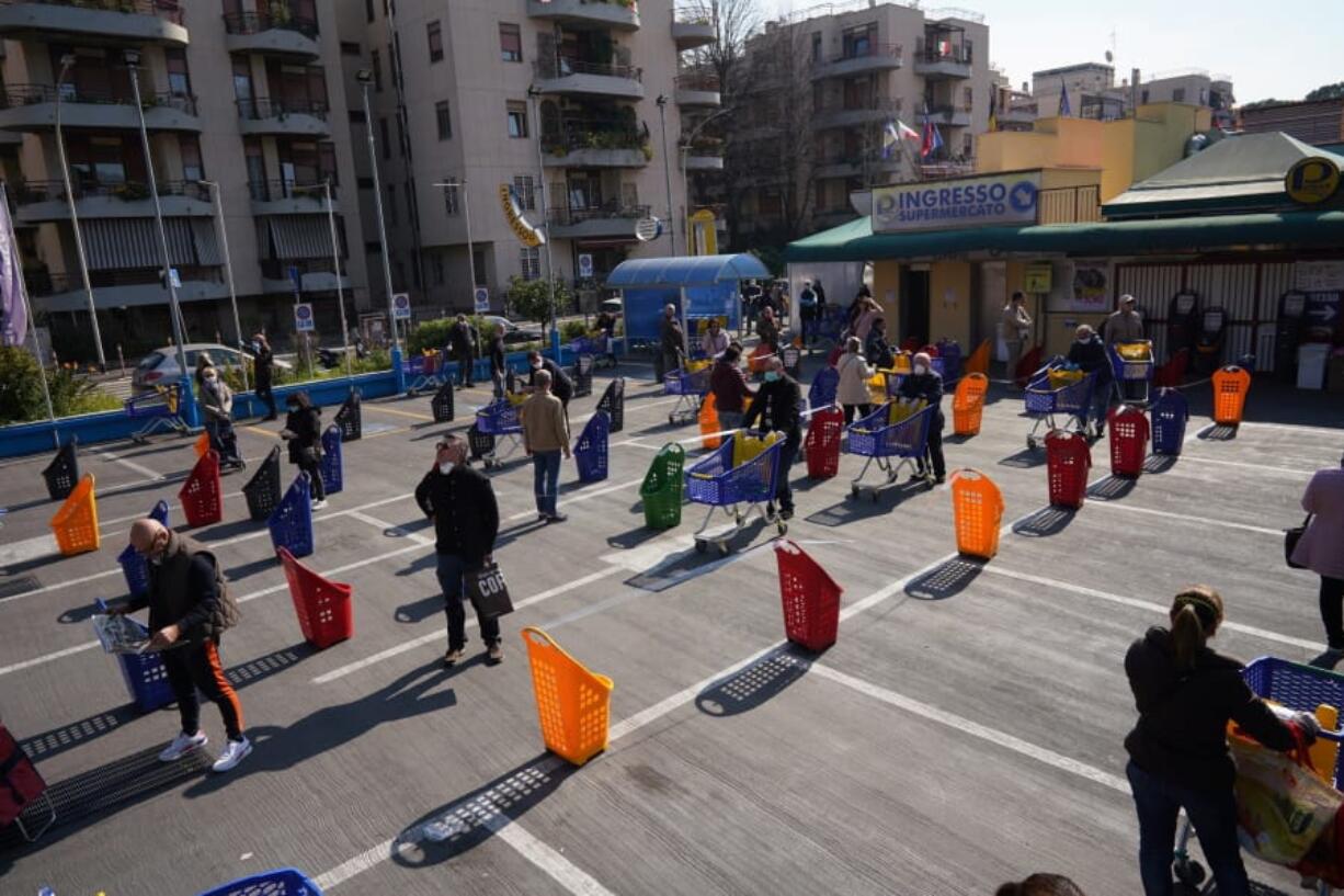 People stand apart as they line up to enter a supermarket in Rome, Friday, March 20, 2020. For most people, the new coronavirus causes only mild or moderate symptoms. For some it can cause more severe illness.