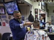 Barber Sami Matta, left, gives a haircut to Steve Perosino, of Dedham, Mass., right, at Chris &amp; Sam&#039;s Barbershop, in Norwood, Mass., Monday, March 23, 2020. The Barbershop is to close by noon Tuesday, March 24, in keeping with Mass. Gov. Charlie Baker&#039;s order that all non-essential businesses close at noon Tuesday and remain closed through Tuesday, April 7, out of concern about the spread of the coronavirus. For most people, the new coronavirus causes only mild or moderate symptoms, such as fever and cough. For some, especially older adults and people with existing health problems, it can cause more severe illness, including pneumonia. The vast majority of people recover from the new virus.