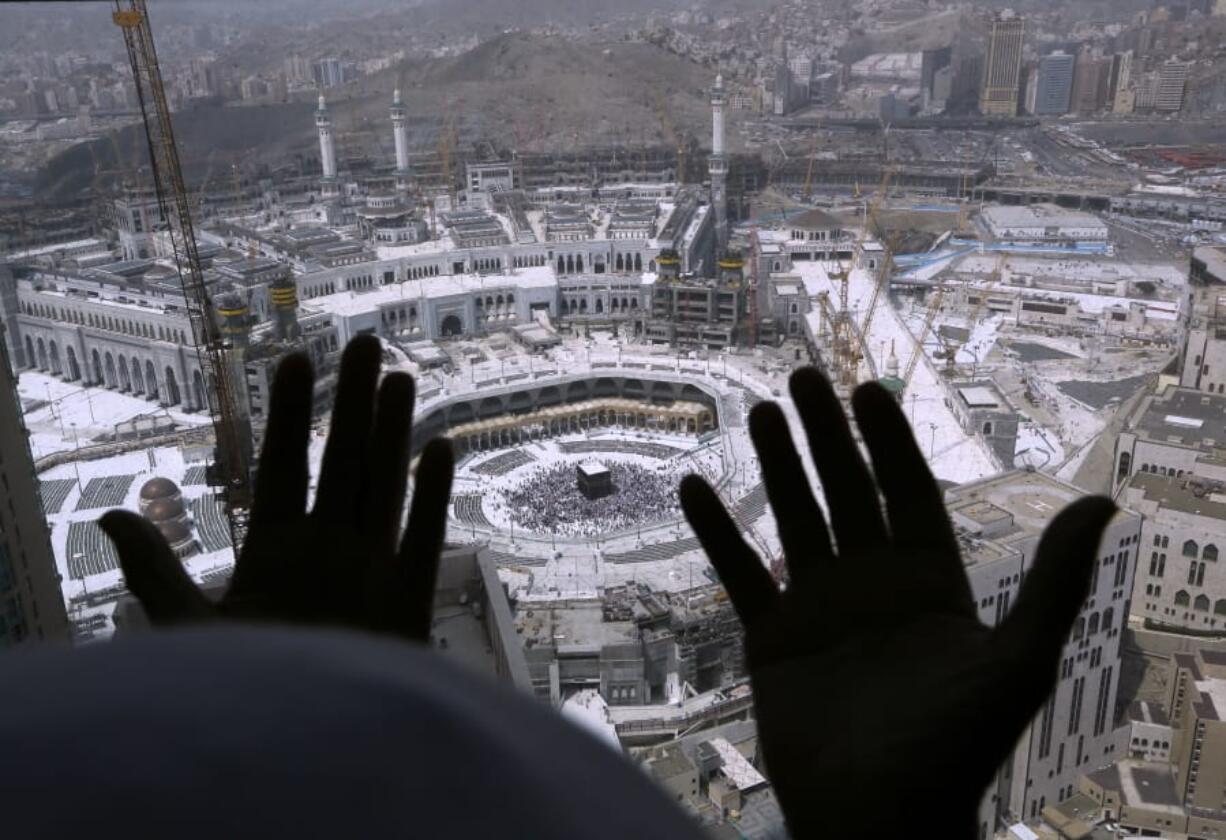 A Muslim prays from a hotel overlooking the Kaaba, the cubic building at the Grand Mosque, in the Muslim holy city of Mecca, Saudi Arabia, Wednesday, March 4, 2020. On Wednesday, Saudi Arabia&#039;s Deputy Health Minister Abdel-Fattah Mashat was quoted on the state-linked news site Al-Yaum saying that groups of visitors to Mecca from inside the country would now also be barred from performing the pilgrimage, known as the umrah.