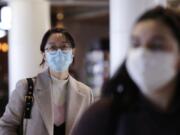 Travelers at Seattle-Tacoma International Airport wear masks Tuesday, March 3, 2020, in SeaTac, Wash. Six of the 18 Western Washington residents with the coronavirus have died as health officials rush to test more suspected cases and communities brace for spread of the disease. All confirmed cases of the virus in Washington are in Snohomish and King counties.