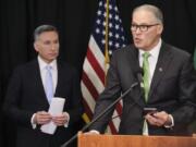 Washington Gov. Jay Inslee reads from an email from his mobile phone as he talks to reporters while King County Executive Dow Constantine listens, Wednesday, March 11, 2020, during a news conference in Seattle. In efforts to slow the spread of the coronavirus, Inslee announced a ban on large public gatherings in three counties in the metro Seattle area.  The vast majority of people recover from the new coronavirus. According to the World  Health Organization, most people recover in about two to six weeks, depending on the severity of the illness.