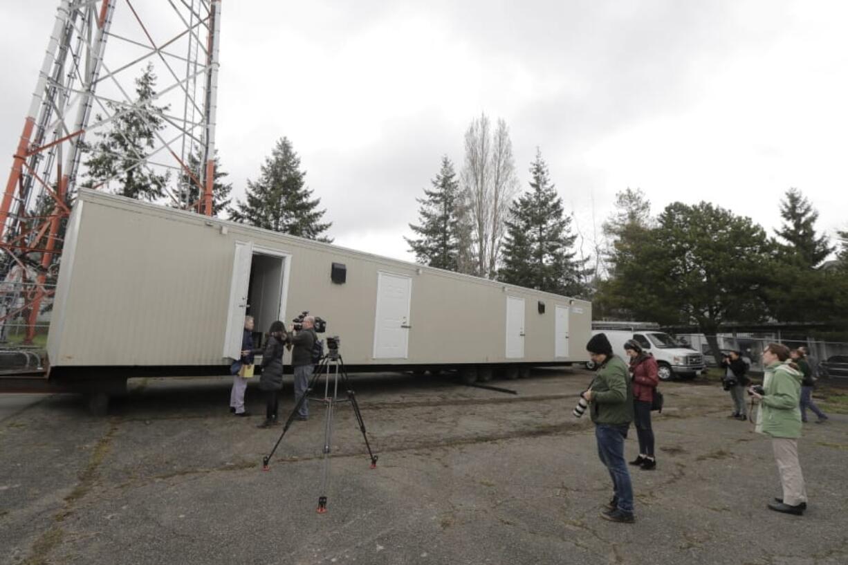 Reporters and photographers work Tuesday, March 3, 2020, at the site in South Seattle where King County will be placing several temporary housing units like the one shown here to house patients undergoing treatment and isolation in response to the COVID-19 coronavirus. (AP Photo/Ted S.