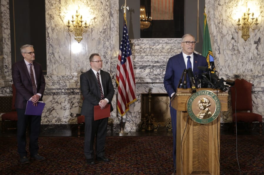 Gov. Jay Inslee, right, talks to the media about the decision to close schools in three counties in response to COVID-19, on March 12 in Olympia. At left are state Health Secretary John Wiesman, and Superintendent of Public Instruction Chris Reykdal.