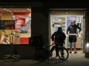 A man uses his elbow to open the door as he walks out of a Domino&#039;s Pizza restaurant in downtown Seattle as a delivery driver walks in Sunday. Washington Gov. Jay Inslee said Sunday night that he would order all bars, restaurants, entertainment and recreation facilities in the state to temporarily close to fight the spread of the COVID-19 coronavirus. Inslee said that restaurants could continue takeout and delivery services. (Ted S.