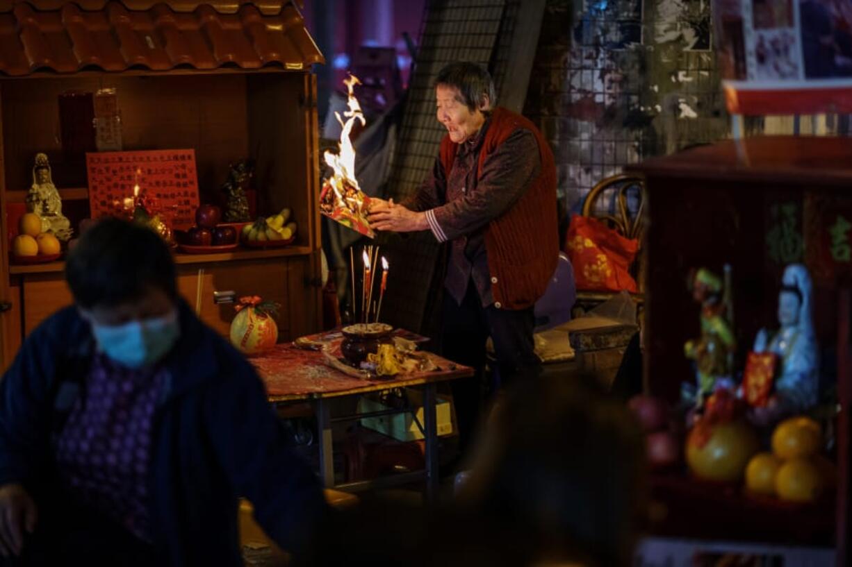 Grandma Leung waves a flaming item around to ward off bad luck as she prepares a &quot;villain hitting&quot; ceremony in the Causeway Bay district of Hong Kong on March 12, 2020.