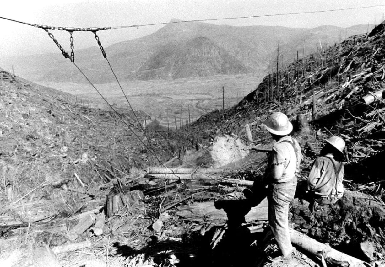 Loggers watch as logs are salvaged above the Toutle River valley in this 1980s Daily News file photo.