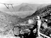 Loggers watch as logs are salvaged above the Toutle River valley in this 1980s Daily News file photo.