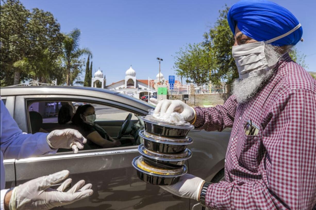 Balwinder Sidhu, right, gives a hand in food distribution April 23 organized by United Sikh Mission and the Sikh Community of Riverside at Sikh Gurdwara in Riverside, Calif.