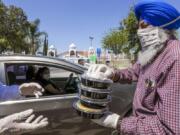 Balwinder Sidhu, right, gives a hand in food distribution April 23 organized by United Sikh Mission and the Sikh Community of Riverside at Sikh Gurdwara in Riverside, Calif.