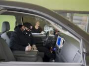 Vancouver resident Ruben Renteria, foreground, checks out his receipt while teller Melissa Engler looks on as he stops by the Cascade Park Columbia Credit Union Branch drive-thru Thursday afternoon. Banks are still allowed to operate during the COVID-19 pandemic, but most are using drive-thru and appointment-only service.