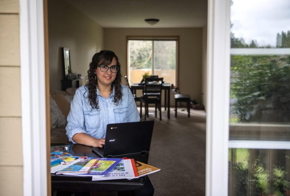 Pioneer Elementary School first-grade dual immersion teacher Melisa Troche is pictured at her home in Vancouver on Wednesday. Teachers throughout the district are preparing to begin virtual learning on Monday. Trouche set up a workspace with class posters and decorations in the background to spruce up her virtual class sessions, as well as books in Spanish she plans to read with her students.