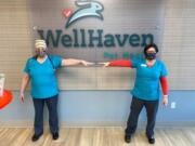 Two employees at WellHaven Pet Health demonstrate social distancing measures while wearing new fabric masks manufactured by Sweet Spot Skirts.