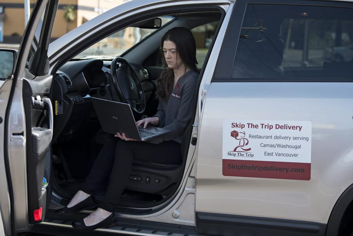 Katie O&#039;Daniel, owner and driver with Skip the Trip Delivery, pauses for a portrait with her laptop in Washougal before making a delivery in Camas.