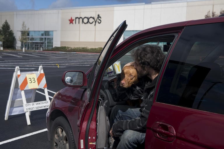 Gerhard Bush-Tschosik of Vancouver shares a kiss with his pit bull mix, Reece, 1, after securing their parking spot at Vancouver Mall on Thursday morning, April 2, 2020. Officials registered car campers vehicles on a first-come, first serve basis starting Thursday.