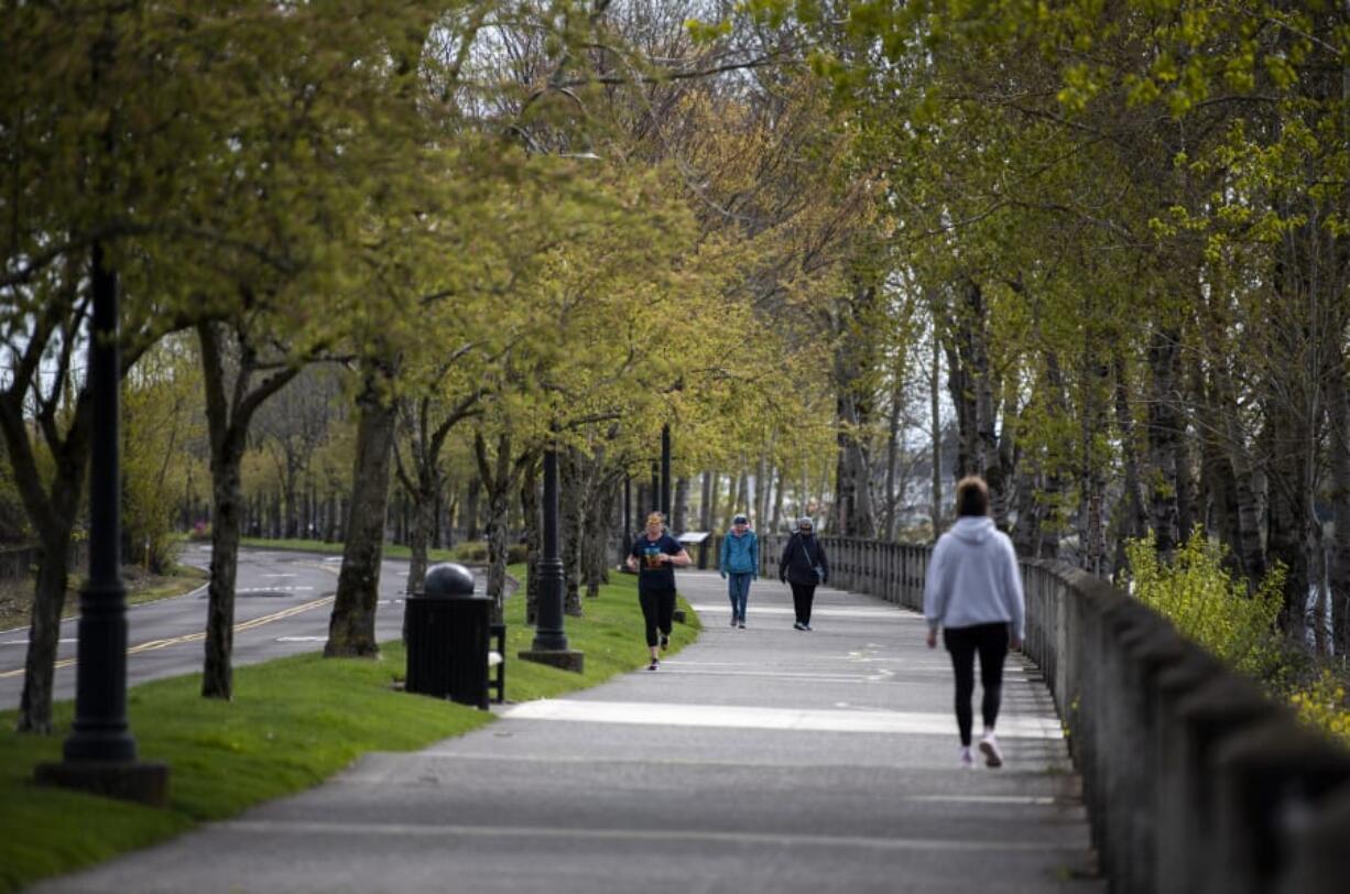 People walk along the Waterfront Renaissance Trail in Vancouver on Tuesday. Authorities hope people continue to practice social distancing as warm weather brings more people outdoors.