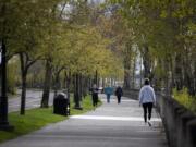 People walk along the Waterfront Renaissance Trail in Vancouver on Tuesday. Authorities hope people continue to practice social distancing as warm weather brings more people outdoors.