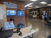 Library staff member Amanda Brown, left, prepares laptops in O&#039;Connell Sports Center for student pickup at Clark College on Monday morning. The college moved almost all its classes online due to shutdown orders connected to the novel coronavirus.