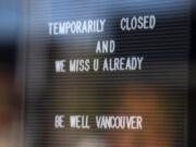 A note to customers is written in the window of a salon in Vancouver.