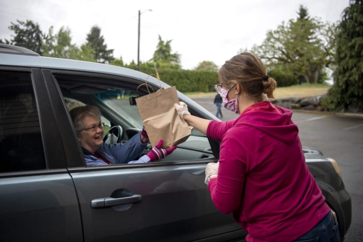 Donna Goff of Vancouver, left, picks up a bag of soup and face masks from Cheri Davis of Woodland on Saturday at Hazel Dell Church of Christ.