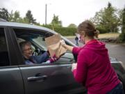 Donna Goff of Vancouver, left, picks up a bag of soup and face masks from Cheri Davis of Woodland on Saturday at Hazel Dell Church of Christ.