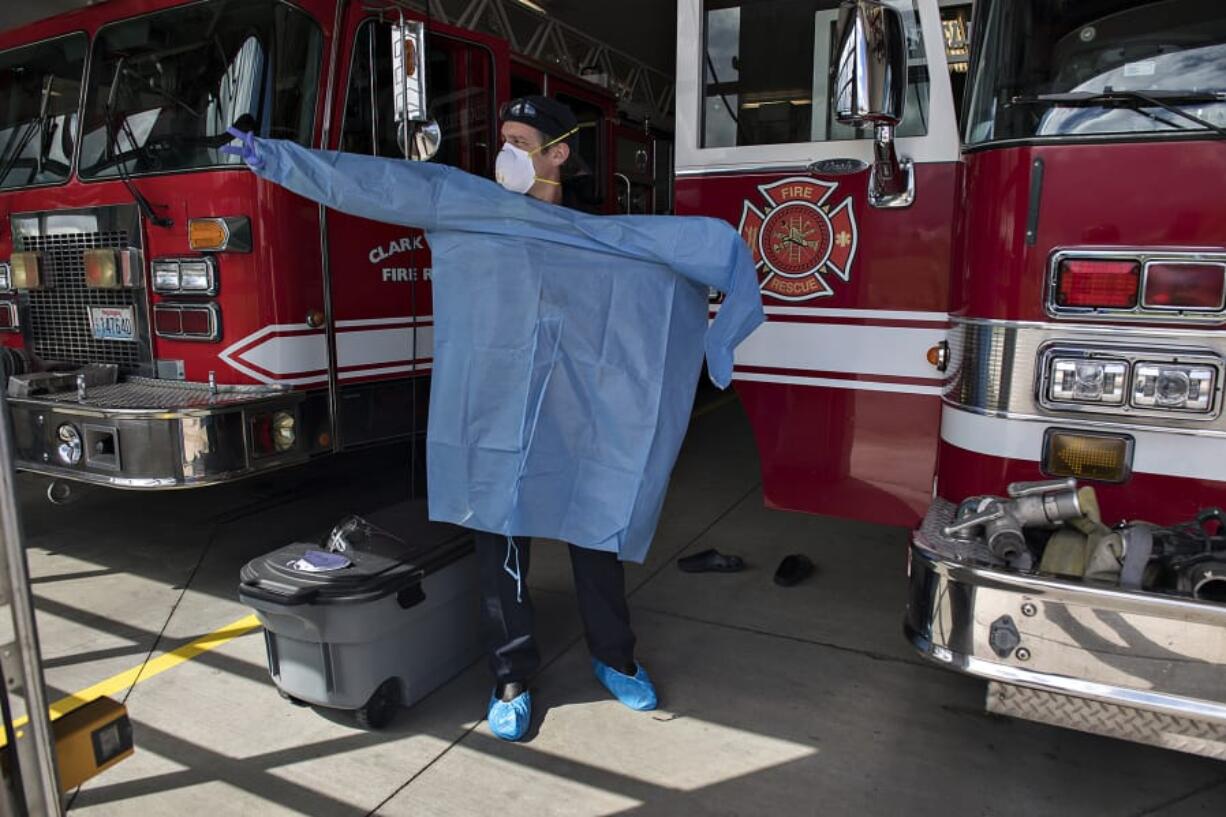 Clark County Fire &amp; Rescue Capt. Blaine Dohman tries on a gown and personal protective equipment at the main station in Ridgefield on Monday. Fire crews with the agency wear the gear when they respond to calls involving people with symptoms associated with COVID-19.