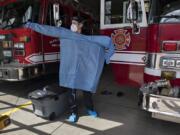 Clark County Fire &amp; Rescue Capt. Blaine Dohman tries on a gown and personal protective equipment at the main station in Ridgefield on Monday. Fire crews with the agency wear the gear when they respond to calls involving people with symptoms associated with COVID-19.