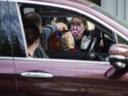 Team manager Krysta States hands an order to customers at Burgerville at the intersection of Fourth Plain Boulevard and Fort Vancouver Way. The Vancouver-based fast food chain has been operating on a drive-thru and delivery-only model since mid-March, and has instituted a number of health safety measures including issuing masks to all employees.