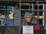 Above, a sign at the Vancouvercenter fourth-tower project site encourages workers to keep a safe distance between each other while working. Health safety signs are one of the new requirements for construction during the COVID-19 pandemic.