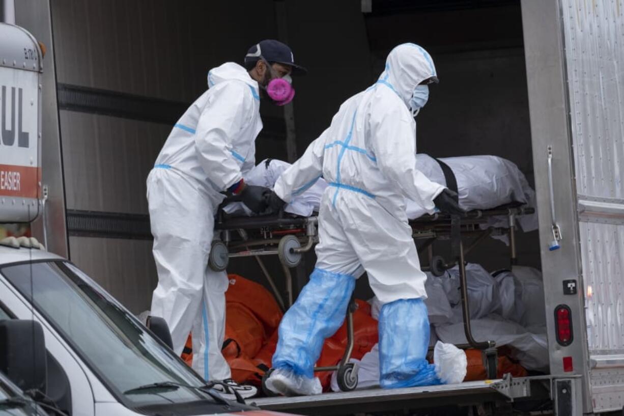 Workers move bodies to a refrigerated truck from the Andrew T. Cleckley Funeral Home in the Brooklyn borough of New York, Wednesday, April 29, 2020. Police responded to a report of human bodies in vehicles, which they determined were connected to the nearby funeral home. The New York Police Department notified the state Department of Health, which oversees funeral homes. The coronavirus pandemic has overrun most funeral homes and morgues in New York City.