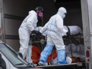 Workers move bodies to a refrigerated truck from the Andrew T. Cleckley Funeral Home in the Brooklyn borough of New York, Wednesday, April 29, 2020. Police responded to a report of human bodies in vehicles, which they determined were connected to the nearby funeral home. The New York Police Department notified the state Department of Health, which oversees funeral homes. The coronavirus pandemic has overrun most funeral homes and morgues in New York City.