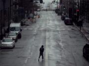 FILE - In this April 3, 2020, file photo a man crosses an empty street in downtown Kansas City, Mo. Americans are increasingly taking preventative measures, including staying away from large crowds and avoiding touching their hands to their faces, amid growing fears of infection with COVID-19, a new poll from The Associated Press-NORC Center for Public Affairs Research found.