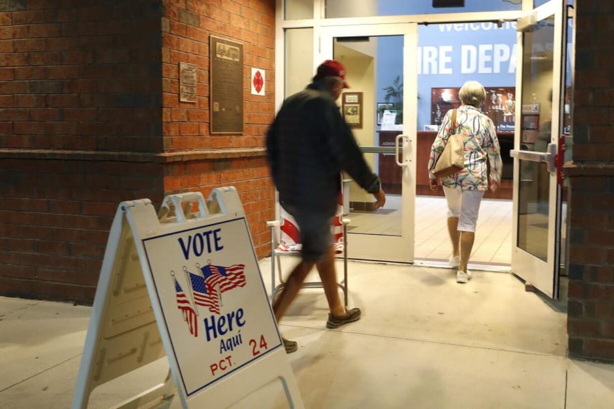 FILE - In this March 17, 2020, file photo voters walk into a polling station for the Florida presidential primary in Bonita Springs, Fla. Scrambling to address voting concerns amid a pandemic, election officials from Nevada to Florida are scaling back or eliminating opportunities for people to cast ballots in person.