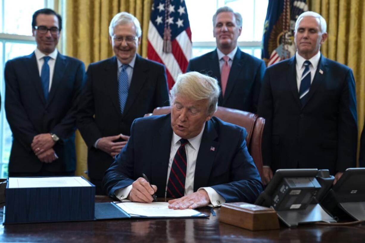 FILE - In this March 27, 2020 file photo, President Donald Trump signs the coronavirus stimulus relief package in the Oval Office at the White House in Washington, as Treasury Secretary Steven Mnuchin, Senate Majority Leader Mitch McConnell, R-Ky., House Minority Leader Kevin McCarty, R-Calif., and Vice President Mike Pence watch. Payments from a federal coronavirus relief package could take several weeks to arrive. While you wait, prep your finances and make a plan for using any money you receive.