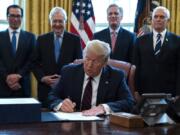 FILE - In this March 27, 2020 file photo, President Donald Trump signs the coronavirus stimulus relief package in the Oval Office at the White House in Washington, as Treasury Secretary Steven Mnuchin, Senate Majority Leader Mitch McConnell, R-Ky., House Minority Leader Kevin McCarty, R-Calif., and Vice President Mike Pence watch. Payments from a federal coronavirus relief package could take several weeks to arrive. While you wait, prep your finances and make a plan for using any money you receive.