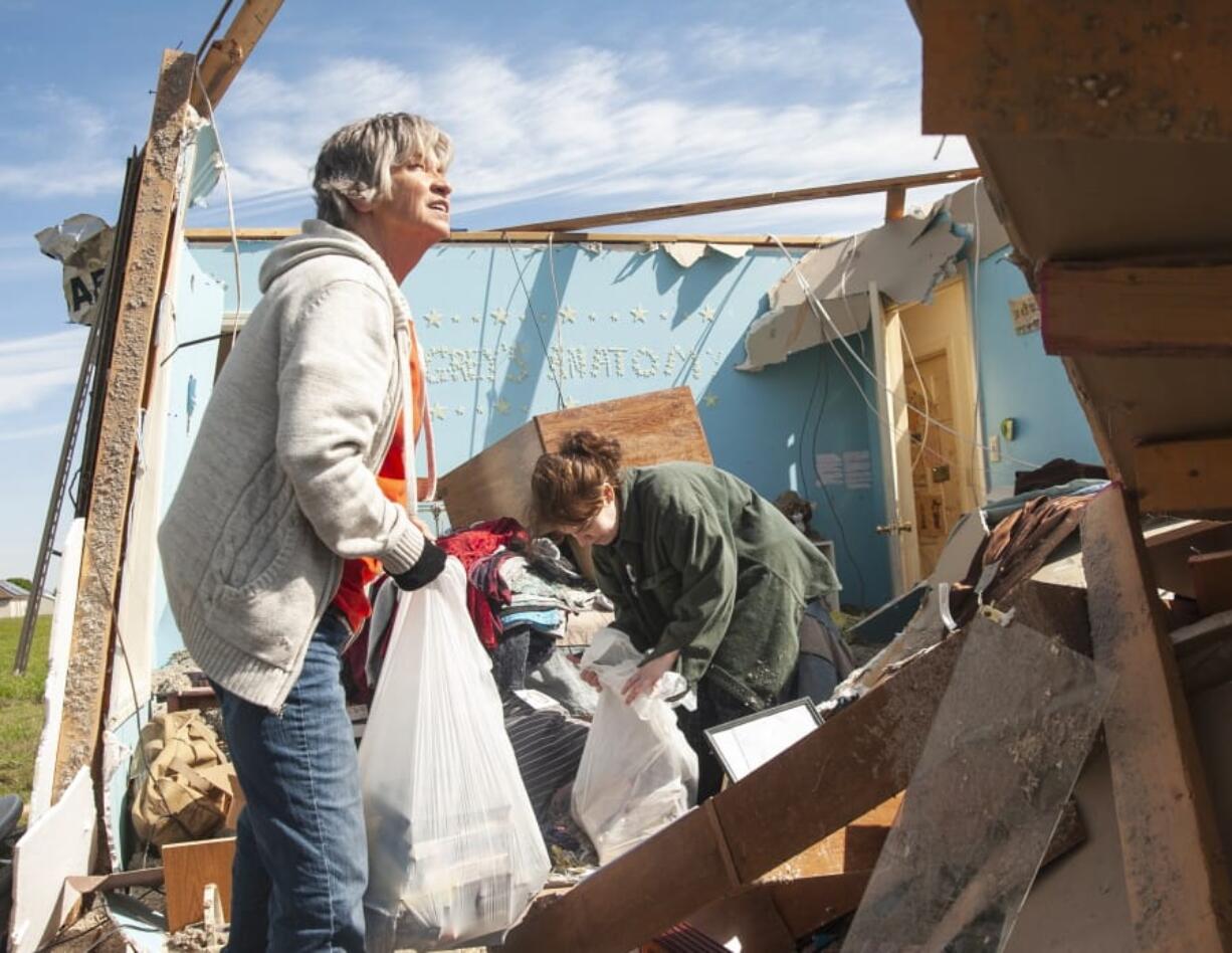 Stephanie Fatheree, right, salvages items from her house damaged from the tornado the previous night with help from a neighbor on Thursday in Harrisburg, Ark.