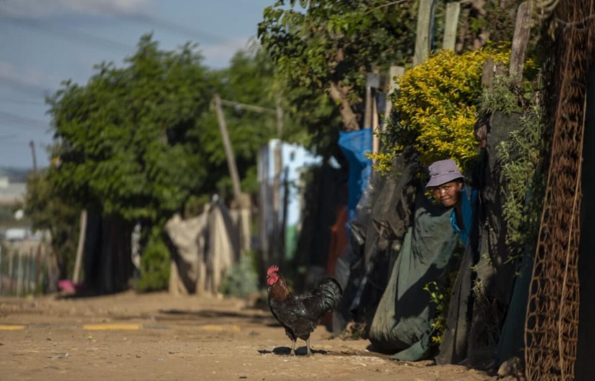 A woman watches as the South African National Defence Forces members patrol the street in Diepsloot informal settlement, north of Johannesburg, South Africa, Thursday, April 16, 2020.