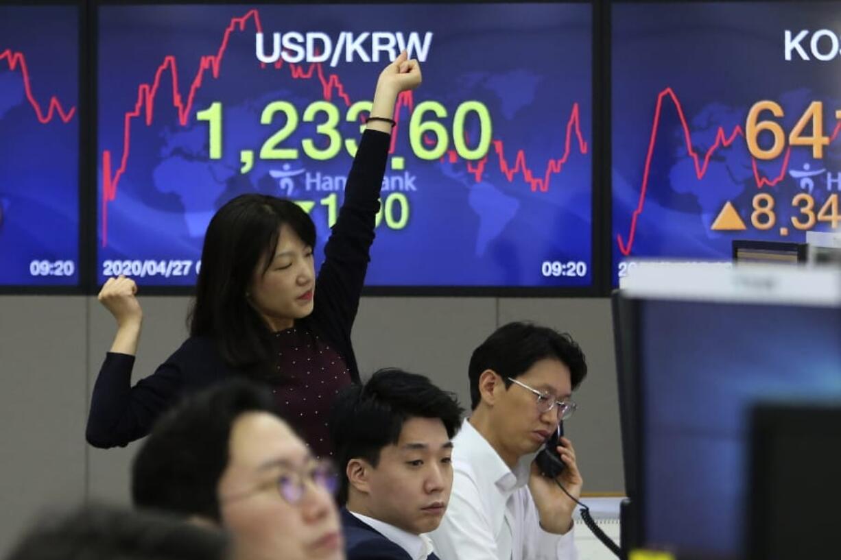 A currency trader stretches at the foreign exchange dealing room of the KEB Hana Bank headquarters in Seoul, South Korea, Monday, April 27, 2020. Asian stock markets have gained after Japan&#039;s central bank promised to buy more government bonds to support financial markets as investors look to central bankers to shore up the struggling global economy.