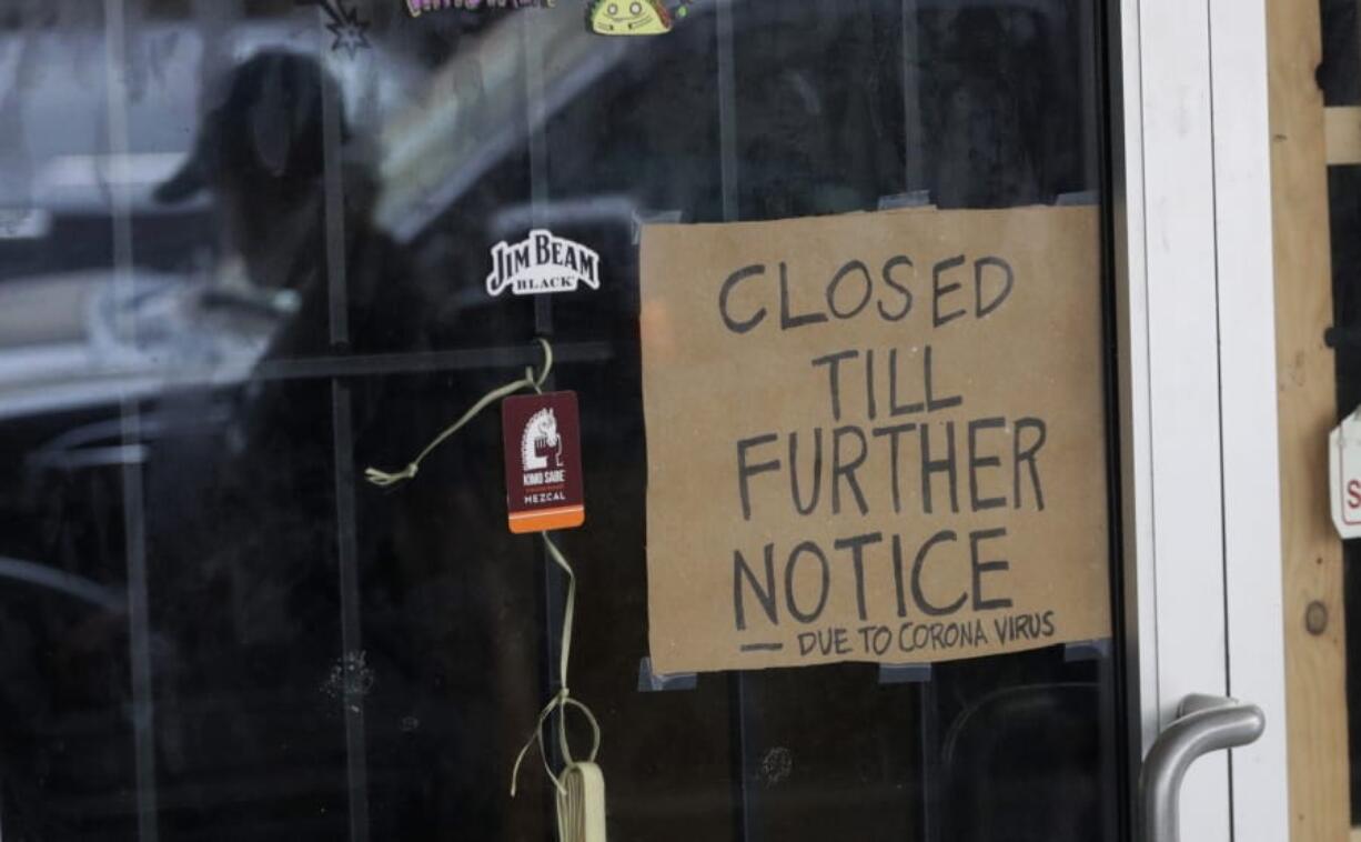 FILE - In this April 22, 2020, file photo, a man wearing a face mask is reflected in the door of a business closed due to the COVID-19 outbreak in San Antonio. President Donald Trump has hinted that he might extend a 60-day hold on green cards that he has ordered to protect American jobs during the coronavirus pandemic.