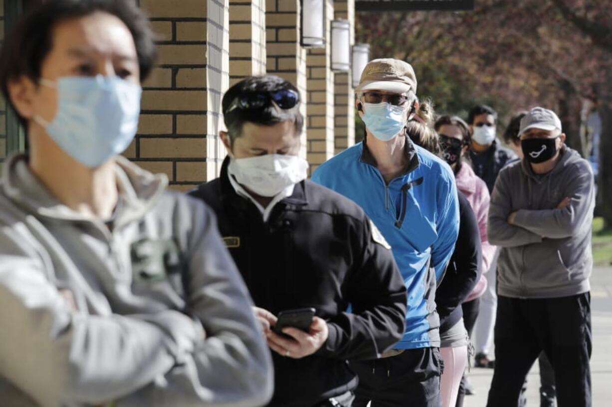 Customers wear a variety of protective masks as they wait some six-feet apart to enter a Trader Joe&#039;s store, where the number of customers allowed inside at any one time was limited because of the coronavirus outbreak, Wednesday, April 8, 2020, in Seattle.