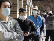 Customers wear a variety of protective masks as they wait some six-feet apart to enter a Trader Joe&#039;s store, where the number of customers allowed inside at any one time was limited because of the coronavirus outbreak, Wednesday, April 8, 2020, in Seattle.