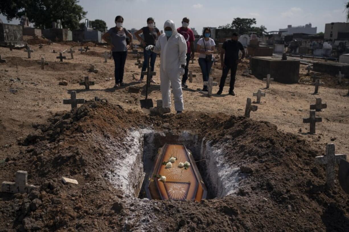 A cemetery worker stands before the coffin containing the remains of Edenir Rezende Bessa, who is suspected to have died of COVID-19, as relatives attend her burial, in Rio de Janeiro, Brazil, Wednesday, April 22, 2020. After visiting 3 primary care health units she was accepted in a hospital that treats new coronavirus cases, where she died on Tuesday. &quot;People need to believe that this is serious, it kills&quot;, said her son Rodrigo Bessa who works at a hospital as nurse in the Espirito Santo state.