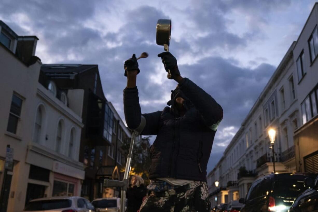 A member of the public bangs a pot outside the Chelsea and Westminster Hospital  to salute local heroes during Thursday&#039;s nationwide Clap for Carers NHS initiative to applaud workers fighting the coronavirus pandemic, in London, Thursday, April 2, 2020. The new coronavirus causes mild or moderate symptoms for most people, but for some, especially older adults and people with existing health problems, it can cause more severe illness or death.