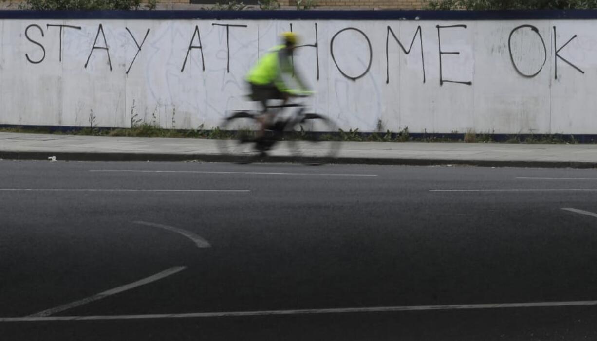 A cyclist passes graffiti as the country continues in lockdown to help curb the spread of the coronavirus, in London, Monday, April 13, 2020. The new coronavirus causes mild or moderate symptoms for most people, but for some, especially older adults and people with existing health problems, it can cause more severe illness or death.