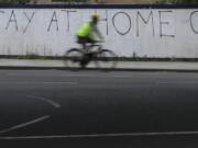 A cyclist passes graffiti as the country continues in lockdown to help curb the spread of the coronavirus, in London, Monday, April 13, 2020. The new coronavirus causes mild or moderate symptoms for most people, but for some, especially older adults and people with existing health problems, it can cause more severe illness or death.