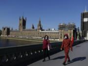 People wear masks as they walk near Britain&#039;s Houses of Parliament as the country is in lockdown to help curb the spread of coronavirus, in London, Tuesday, April 21, 2020. Britain&#039;s Parliament is going back to work, and the political authorities have a message for lawmakers: Stay away. U.K. legislators and most parliamentary staff were sent home in late March as part of a nationwide lockdown to slow the spread of the new coronavirus.