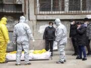 FILE - In this Feb. 1, 2020, file photo, funeral home workers remove the body of a person suspected to have died from the coronavirus outbreak from a residential building in Wuhan in central China&#039;s Hubei Province. The central Chinese city of Wuhan has raised its number of COVID-19 fatalities by more than 1,000. State media said the undercount had been due to the insufficient admission capabilities at overwhelmed medical facilities at the peak of the outbreak.