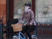 A bicyclist wears face protection against the new coronavirus while pedaling through Larimer Square early Saturday, April 25, 2020, in downtown Denver.